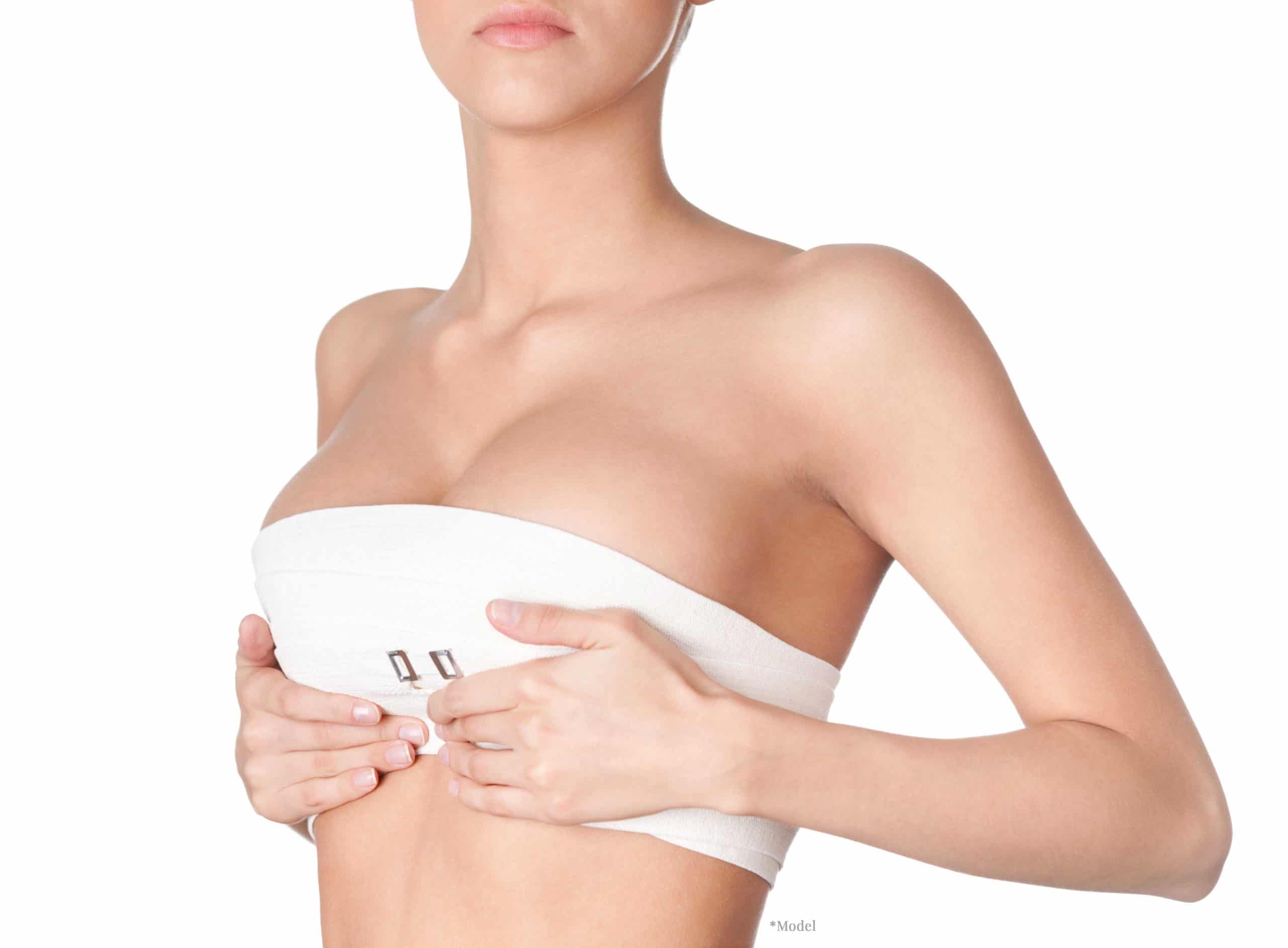White female holding up her breasts wearing a compressions garment