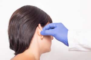 A plastic surgeon doctor examines a patient s girl s ears before performing an otoplasty surgery