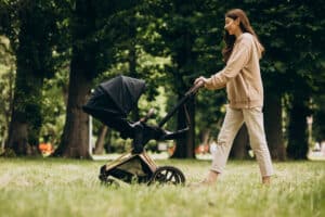 Mom walking in the park pushing her baby stroller, recovering from mommy makeover