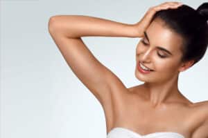 Woman holding her arm to her head showing her slim, toned arms from liposuction