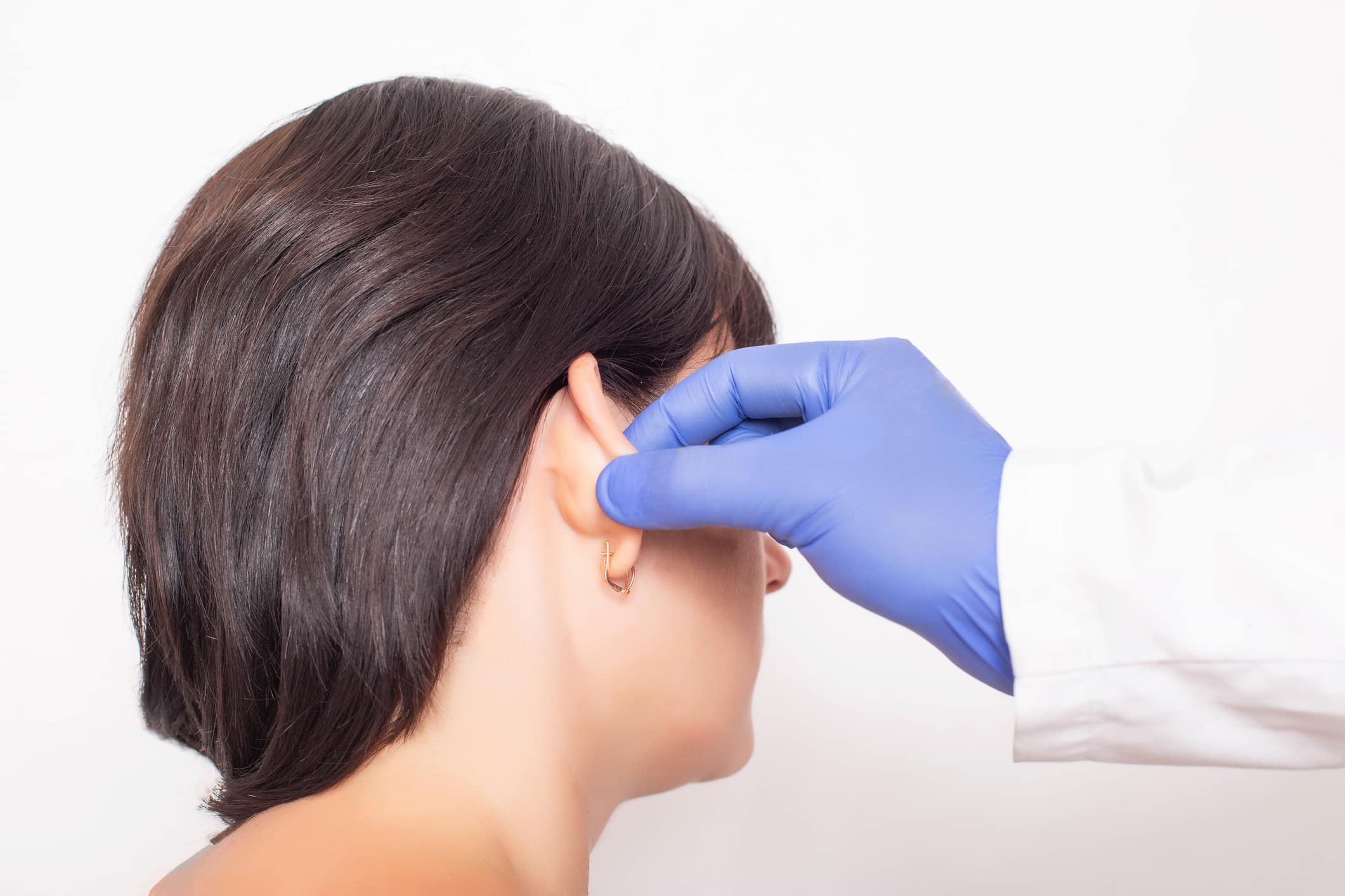 A plastic surgeon doctor examines a patient s girl s ears before performing an otoplasty surgery, close up